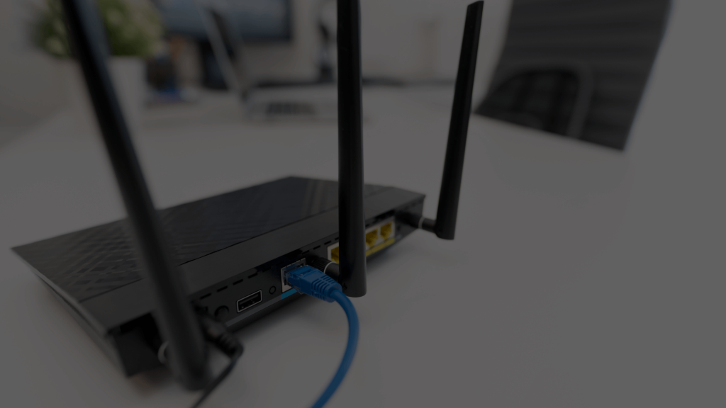 A standard black Wi-Fi router with multiple antennas and a single blue Ethernet cable, representing a typical ISP-provided device, contrasting with professional home networks.